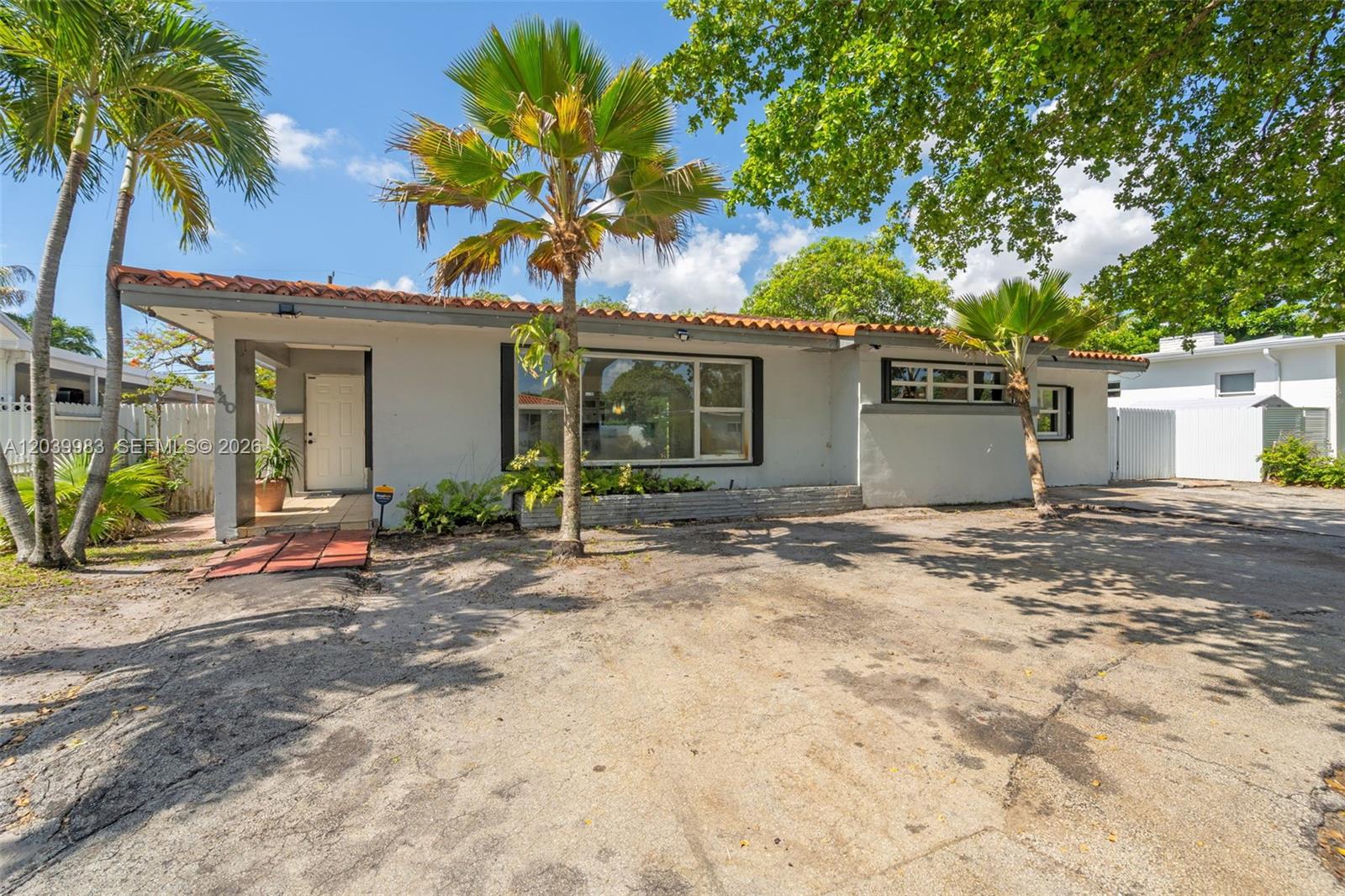 A single-story house with a flat roof, terracotta trim, and a large paved driveway — 440 NW 125th St, North Miami FL 33168, NORTH MIAMI, FL