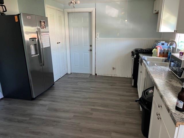 A kitchen features stainless steel appliances, white cabinets, and gray wood-look flooring — 340 PIERCE AVENUE, DAYTONA BEACH, FL