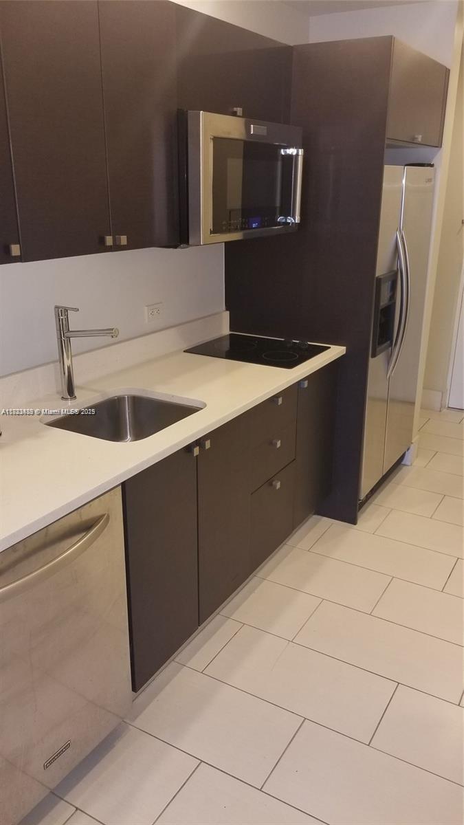 A modern kitchen features dark cabinets, stainless steel appliances, and white countertops — 5300 NW 87th Ave # 415, Doral FL 33178, DORAL, FL