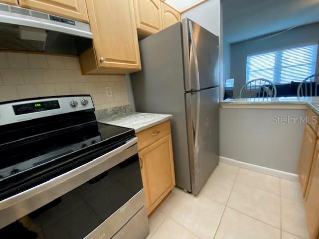 A kitchen features light wood cabinets, stainless steel appliances, and a tiled backsplash — 7321 CENTRAL AVENUE UNIT 202, ST PETERSBURG, FL