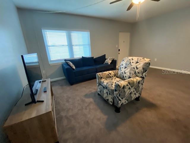 A living room features a blue sofa, a patterned armchair, and a television on a stand — 7321 CENTRAL AVENUE UNIT 202, ST PETERSBURG, FL