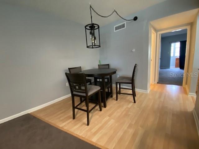 A dining area features a dark wood table with three chairs and a hanging pendant light — 7321 CENTRAL AVENUE UNIT 202, ST PETERSBURG, FL