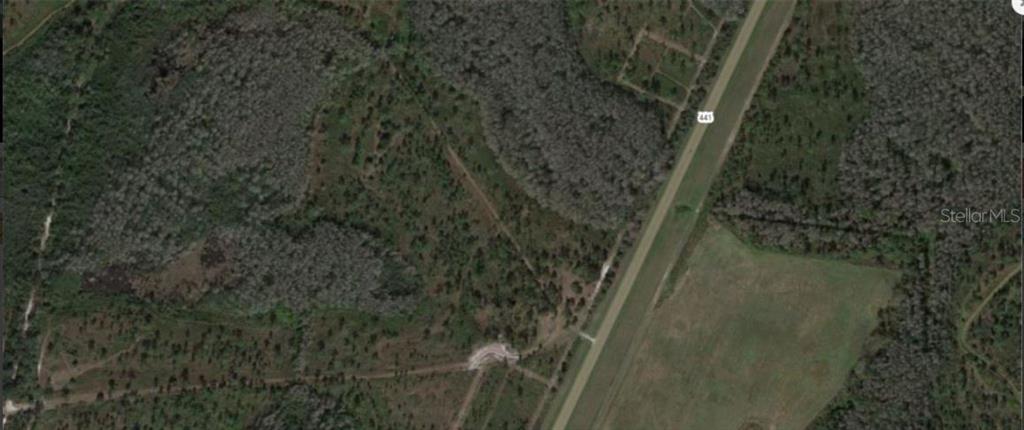 This is an aerial map view showing a highway running alongside wooded and cleared land — S KENANSVILLE ROAD, OKEECHOBEE, FL