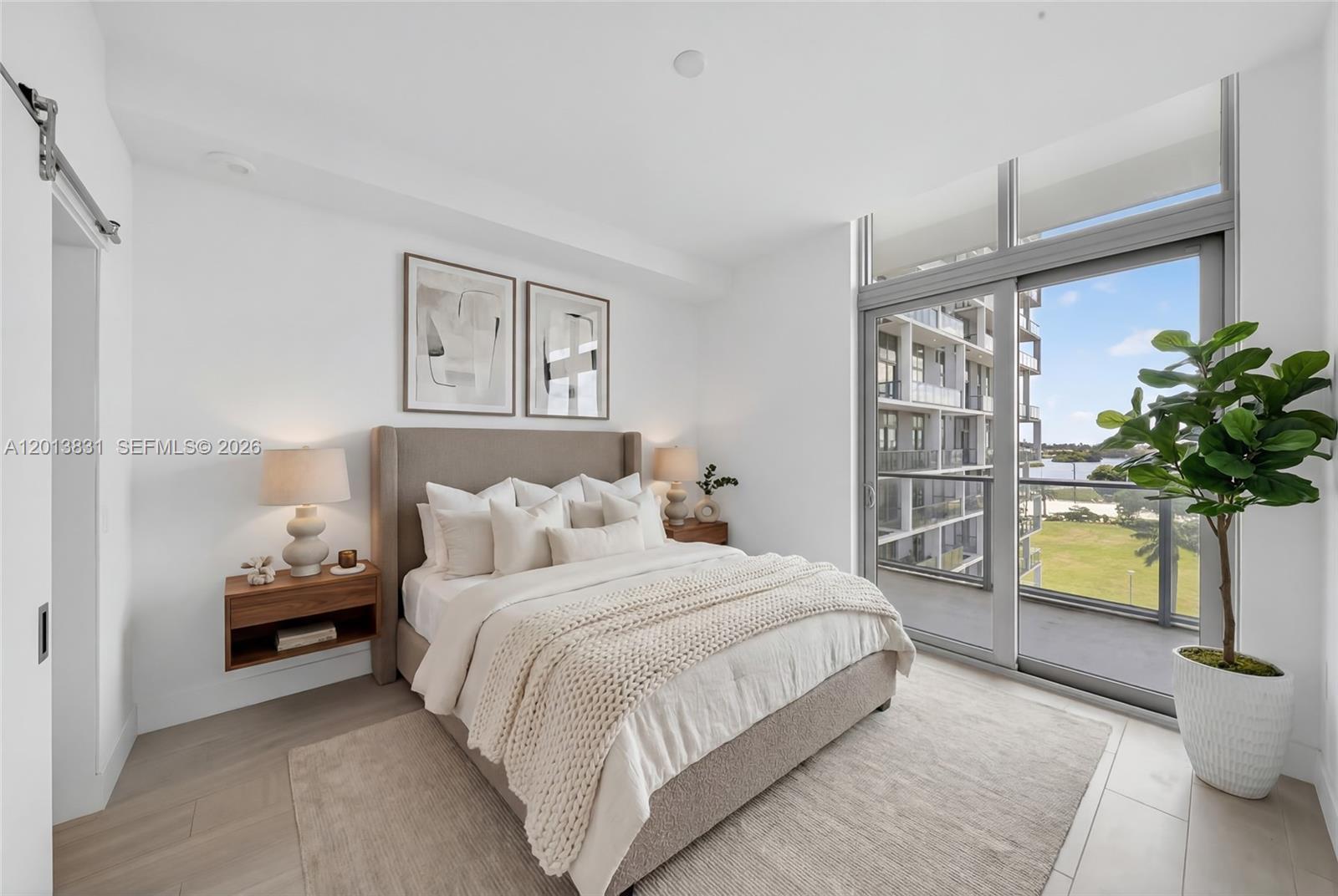 A modern bedroom features a neutral color palette, a bed, and a balcony with views — 2000 Metropica Way # 615, Sunrise FL 33323, SUNRISE, FL