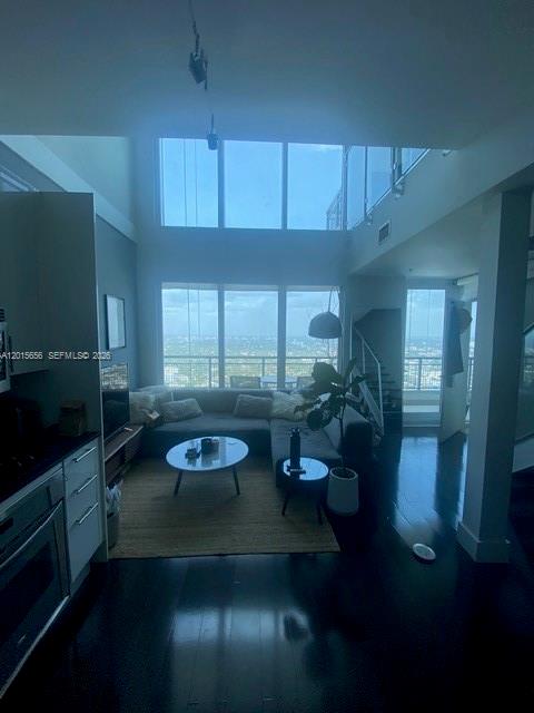 A modern living room with high ceilings, floor-to-ceiling windows, and dark wood flooring — 60 SW 13th St # 4611, Miami FL 33130, MIAMI, FL