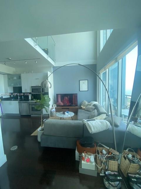 A modern open-concept living room features a grey sectional sofa, a floor lamp, and kitchen — 60 SW 13th St # 4611, Miami FL 33130, MIAMI, FL