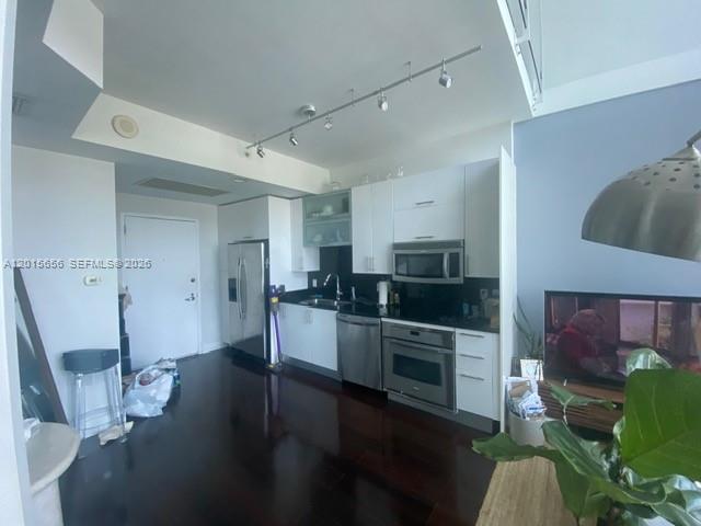A modern kitchen features white cabinetry, stainless steel appliances, and dark wood flooring — 60 SW 13th St # 4611, Miami FL 33130, MIAMI, FL