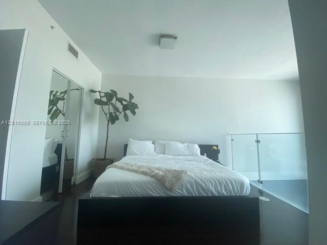 A modern bedroom features a dark bed frame, a potted plant, and a glass railing — 60 SW 13th St # 4611, Miami FL 33130, MIAMI, FL