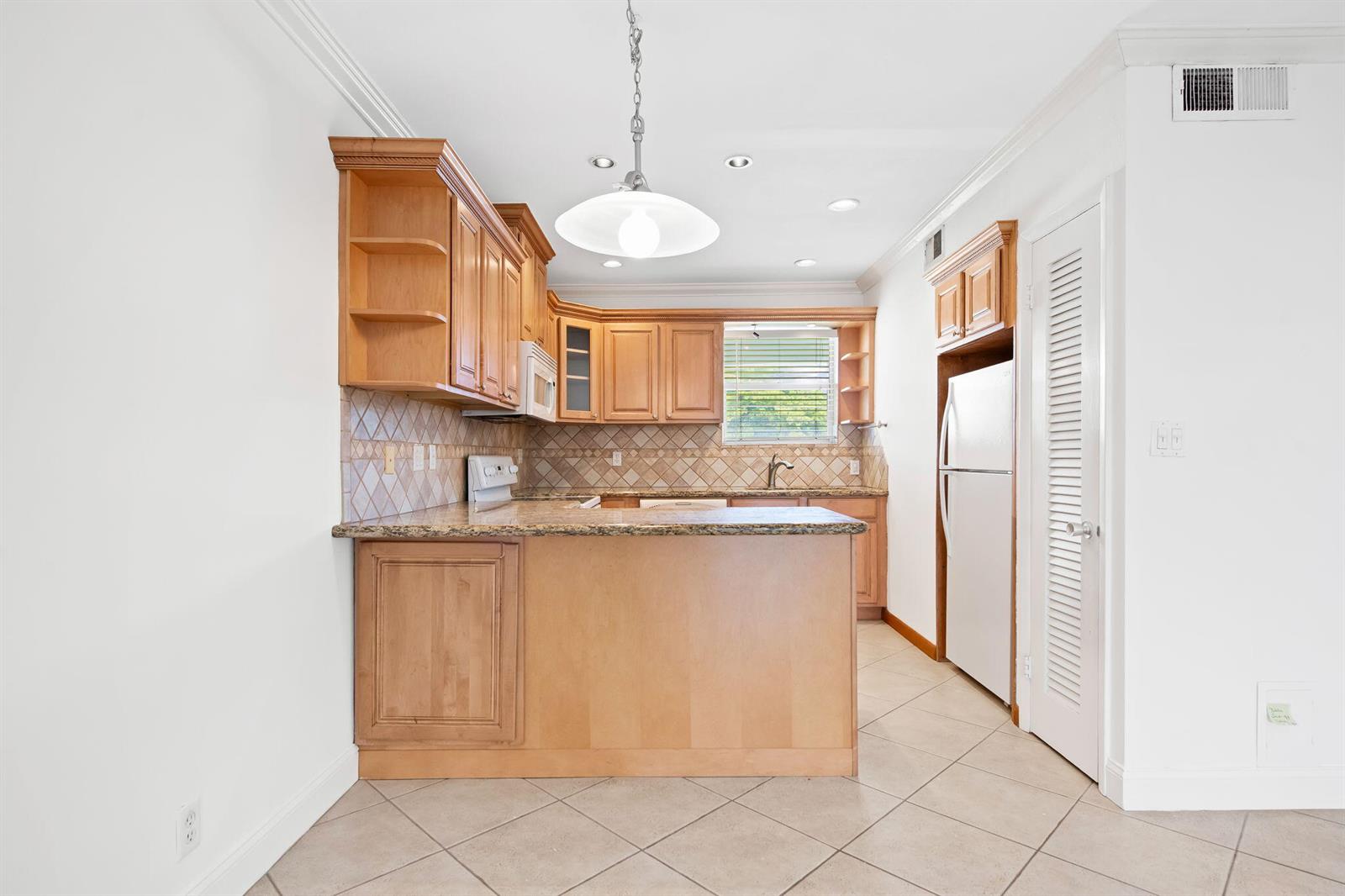 A kitchen features light wood cabinets, granite countertops, a tile backsplash, and tile flooring — 2748 NE 28th Avenue # 20, Lighthouse Point FL 33064, LIGHTHOUSE POINT, FL