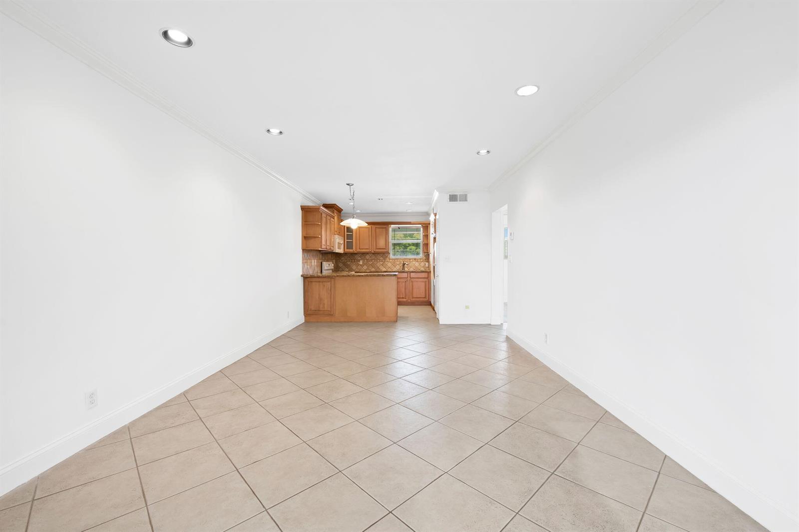 A wide-angle view of an open-concept kitchen with wood cabinets and beige tile flooring — 2748 NE 28th Avenue # 20, Lighthouse Point FL 33064, LIGHTHOUSE POINT, FL