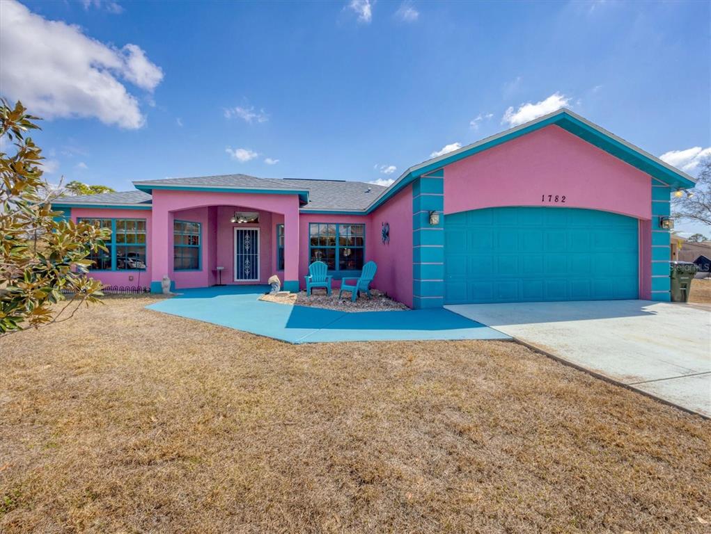 A single-story house with bright pink walls, turquoise trim, and a matching turquoise driveway — 1782 SHEVLIN STREET, NORTH PORT, FL