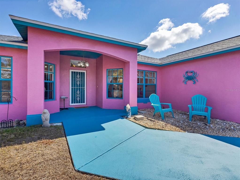 A bright pink house exterior features a blue walkway, blue trim, and two blue chairs — 1782 SHEVLIN STREET, NORTH PORT, FL