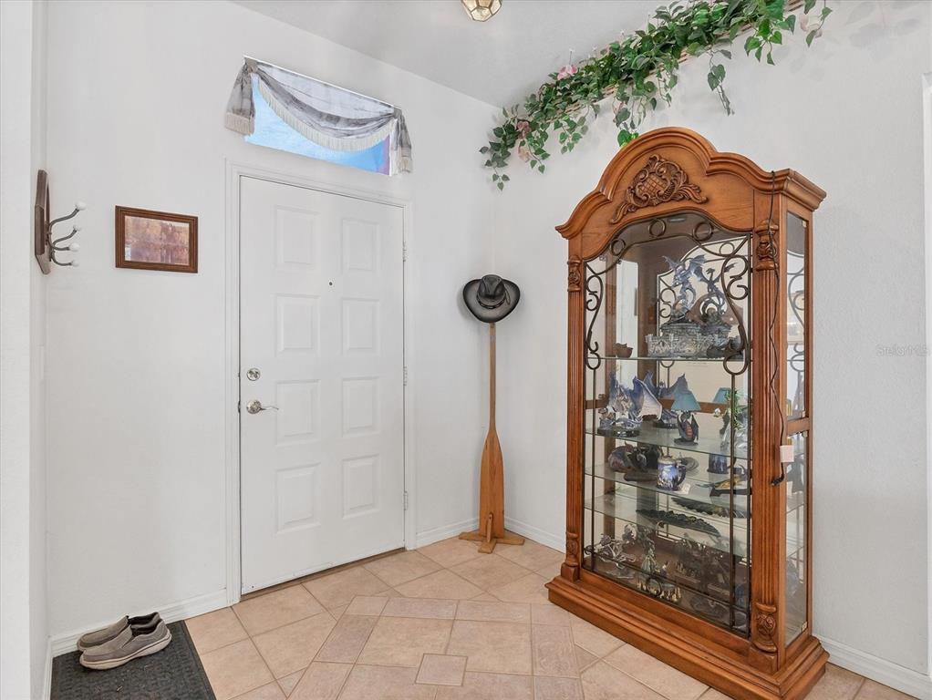 An entryway features tile flooring, a white front door, and a large wooden display cabinet — 1782 SHEVLIN STREET, NORTH PORT, FL