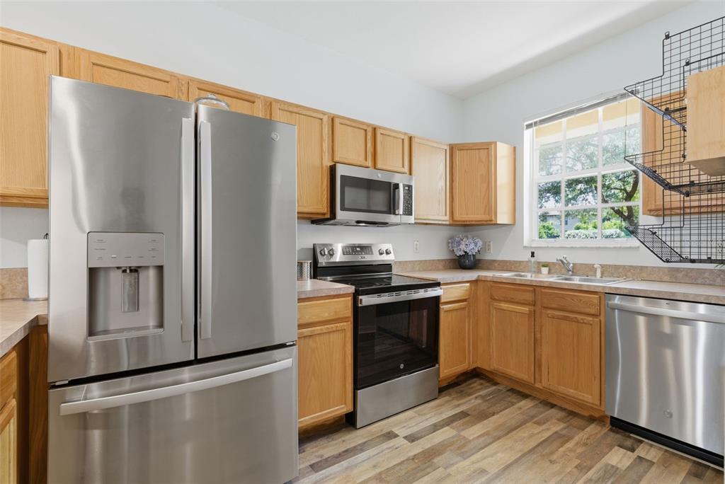 A kitchen with stainless steel appliances, oak cabinets, and wood-look flooring — 2049 FIESTA RIDGE COURT, TAMPA, FL