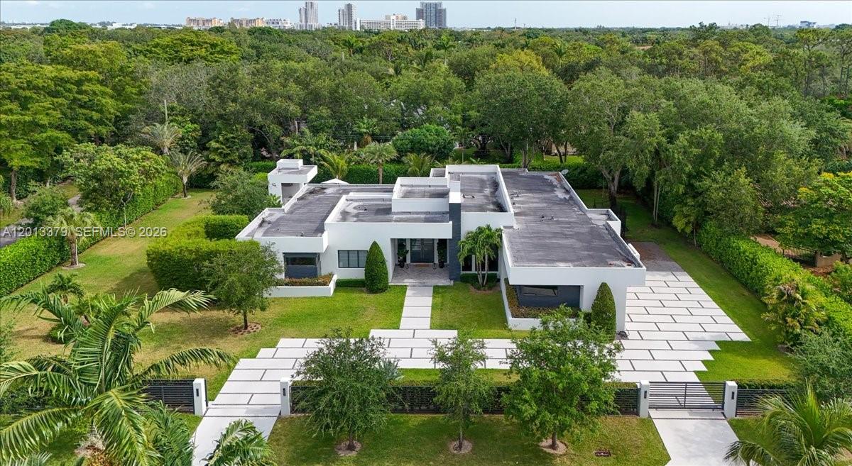 An aerial view of a modern white flat-roofed house with a paved driveway and lawn — 6785 SW 99th Ter, Pinecrest FL 33156, PINECREST, FL
