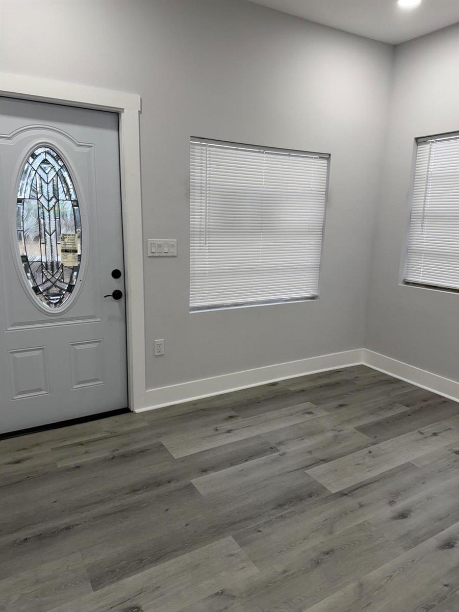 A room with gray walls, wood-look flooring, a white front door, and two windows — 210 Basilan Crescent, Clewiston FL 33440, CLEWISTON, FL