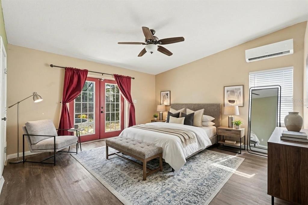 A bedroom with a bed, bench, armchair, and French doors leading to an outdoor area — 805 W COLLEGE AVENUE, RUSKIN, FL