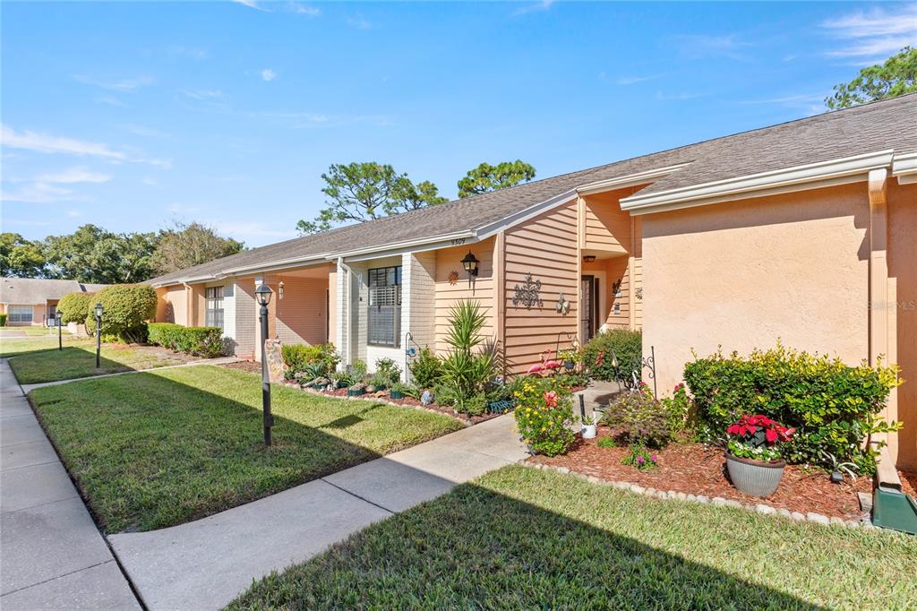 A single-story tan stucco home with a walkway, landscaping, and a covered entryway — 9309 TROWBRIDGE COURT, NEW PORT RICHEY, FL