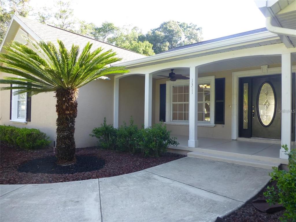 A palm tree stands in front of a house with a covered porch and entryway — 1311 SE 39TH COURT, OCALA, FL