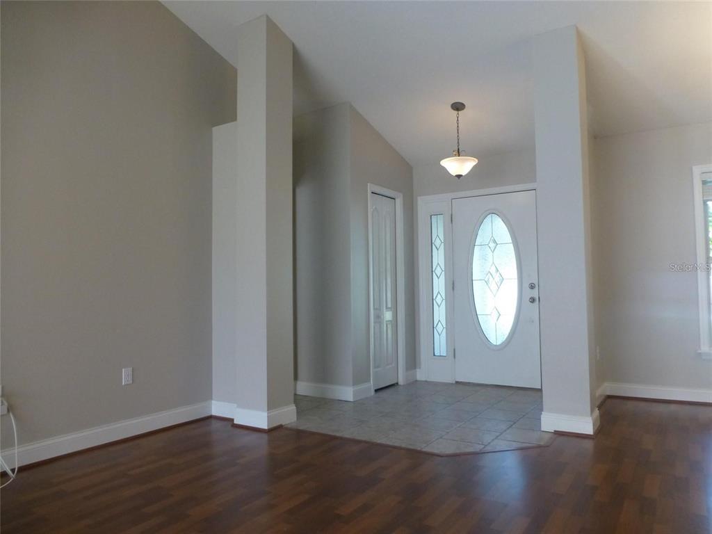 An entryway features a tiled floor, a white front door with glass, and hardwood flooring — 1311 SE 39TH COURT, OCALA, FL