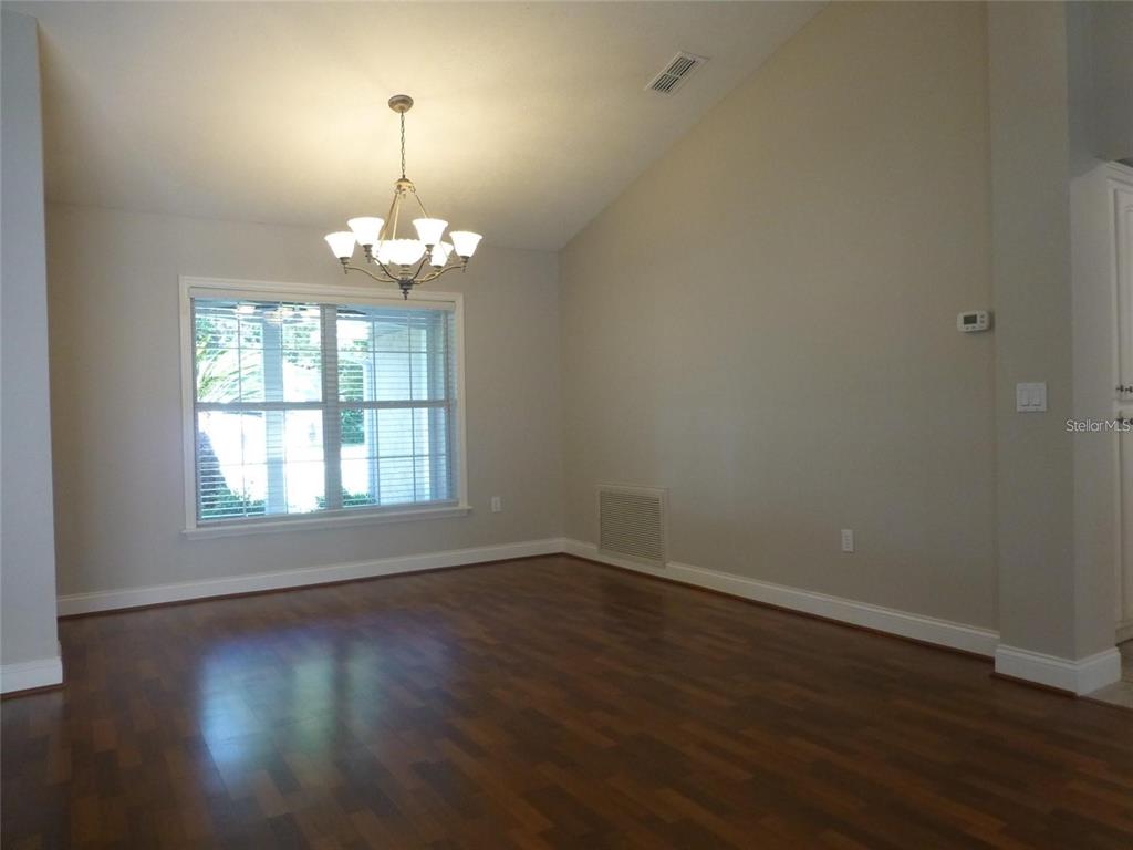 A dining room features dark wood flooring, a vaulted ceiling, and a chandelier — 1311 SE 39TH COURT, OCALA, FL
