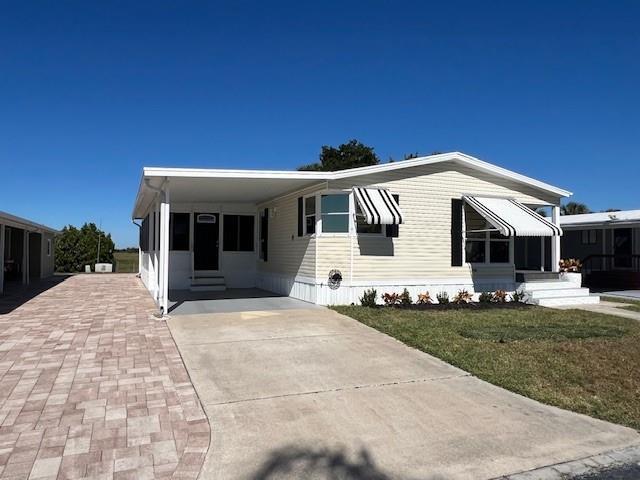 A single-story manufactured home features light siding, a concrete driveway, and a covered carport — 1601 Hwy 441, Okeechobee FL 34974, OKEECHOBEE, FL