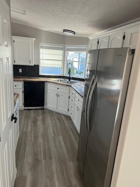 A kitchen features white cabinetry, stainless steel appliances, a black backsplash, and wood-look flooring — 1601 Hwy 441, Okeechobee FL 34974, OKEECHOBEE, FL