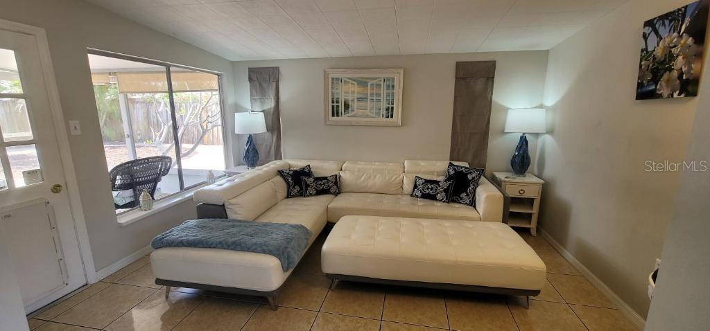 A living room features a white sectional sofa, a matching ottoman, and tile flooring — 3530 SCHWALBE DRIVE, SARASOTA, FL