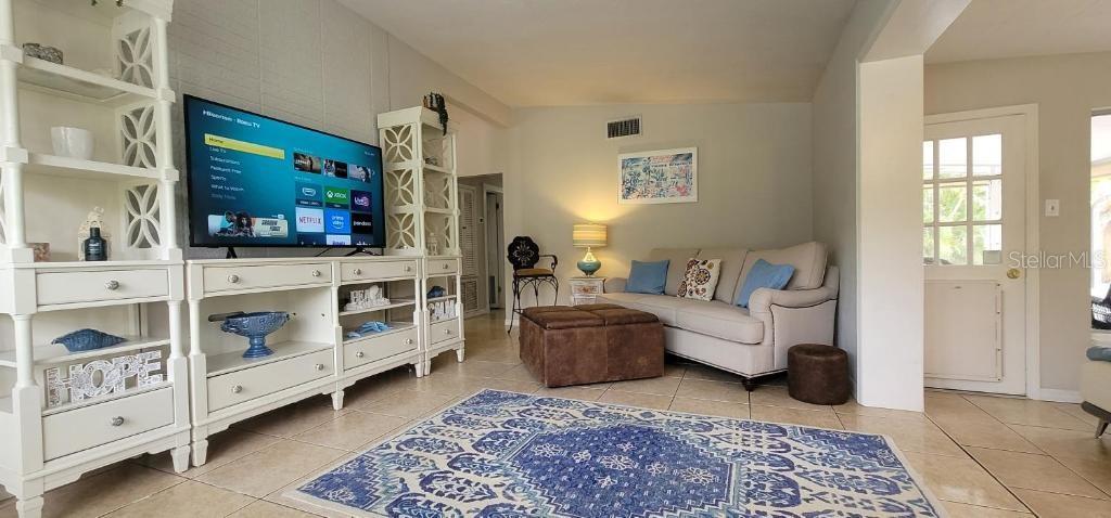 A living room features a television on a white media console, sofa, and area rug — 3530 SCHWALBE DRIVE, SARASOTA, FL