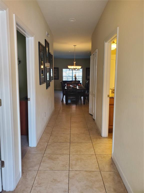 A tiled hallway leads to a dining room with a chandelier and a large window — 8965 CAT PALM ROAD, KISSIMMEE, FL