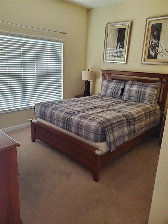 A bedroom features a wooden bed frame with plaid bedding, a bedside lamp, and two framed pictures — 8965 CAT PALM ROAD, KISSIMMEE, FL