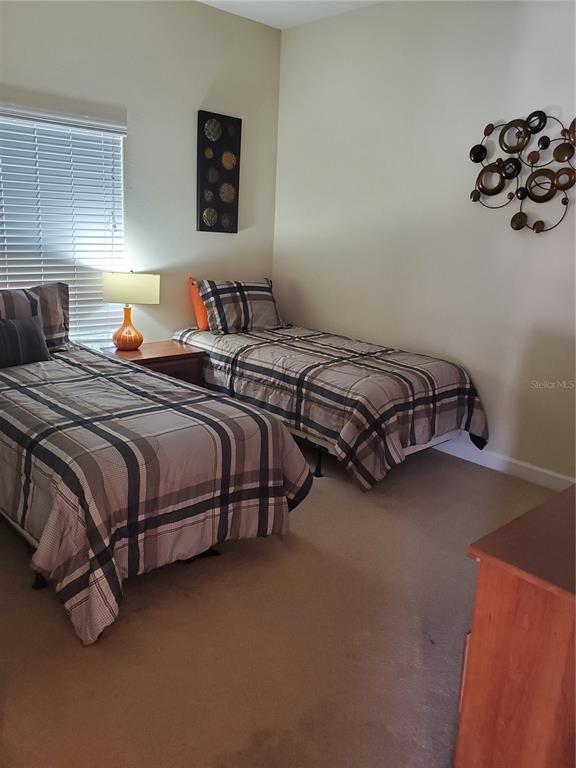 A bedroom features two twin beds with plaid bedding, a nightstand, and wall art — 8965 CAT PALM ROAD, KISSIMMEE, FL
