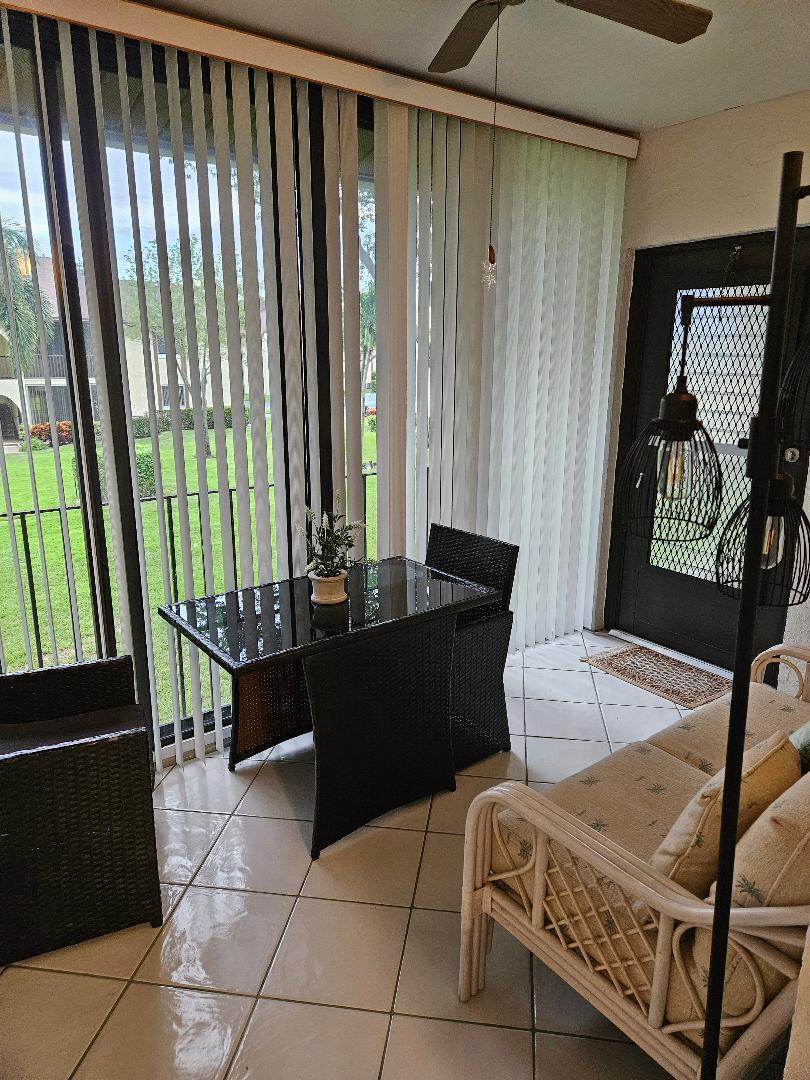 A sunroom features tile flooring, a small dining set, wicker furniture, and vertical blinds — 105 Lake Pine Circle # 2, FL 33463, FL