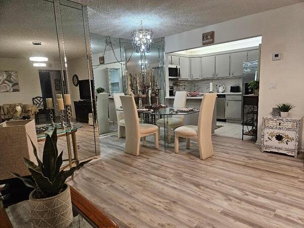 A dining area with a glass table and chairs sits adjacent to a white kitchen — 105 Lake Pine Circle # 2, FL 33463, FL