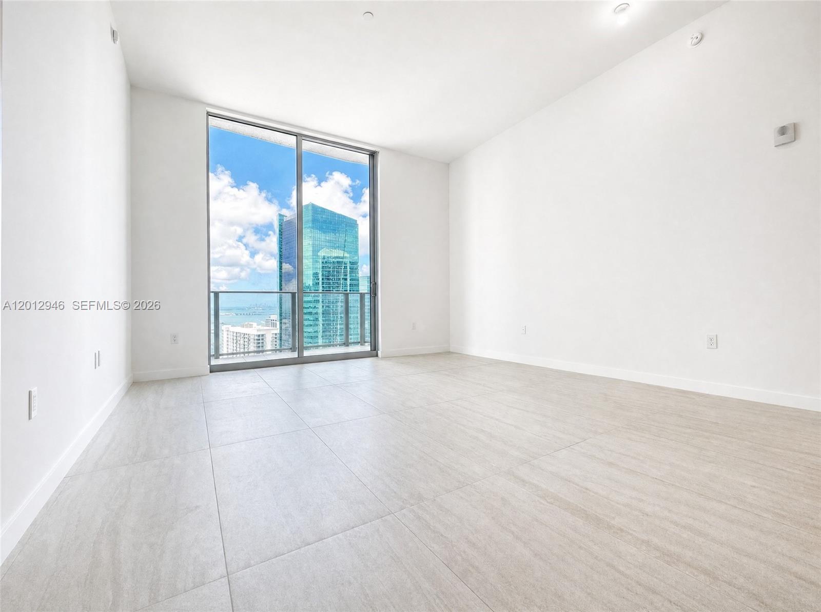 An empty room with white walls, light tile flooring, and a floor-to-ceiling window view — 77 SE 5 ST, Miami FL 33131, MIAMI, FL