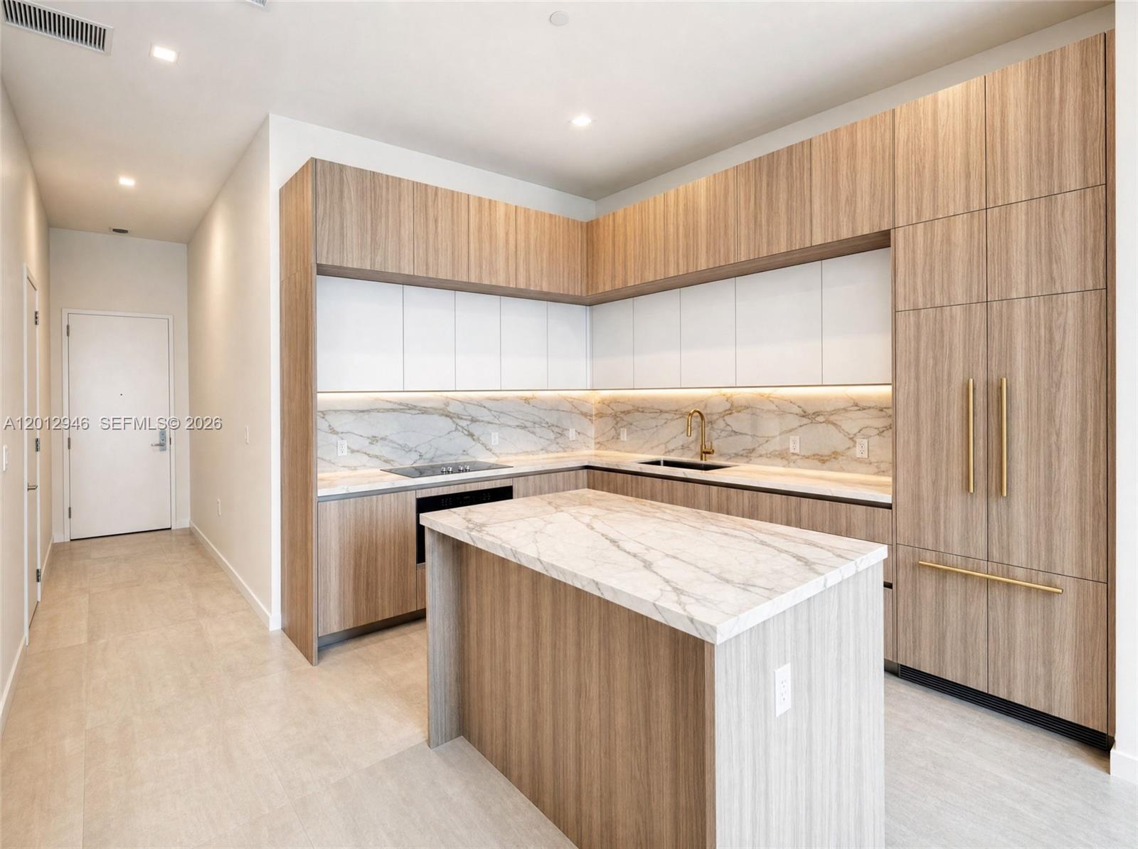 A modern kitchen features wood-grain cabinetry, white upper cabinets, marble countertops, and a central island — 77 SE 5 ST, Miami FL 33131, MIAMI, FL