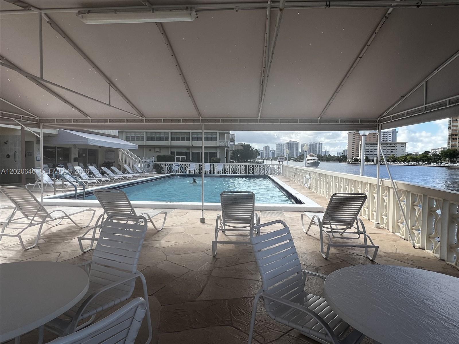 A covered outdoor pool deck features lounge chairs, tables, and views of the waterfront — 1817 S Ocean Dr # 718, Hallandale Beach FL 33009, HALLANDALE BEACH, FL