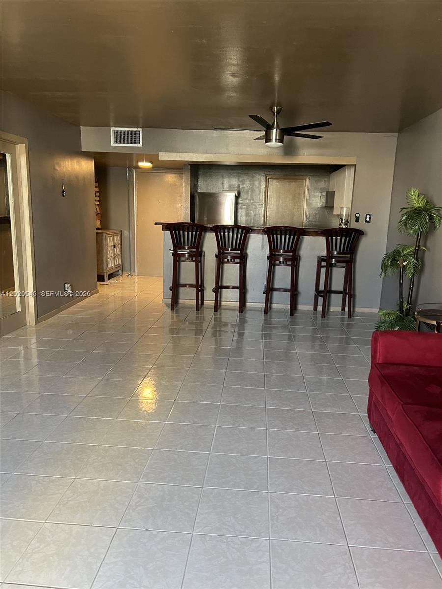 A room with gray walls, tiled floors, a breakfast bar with four stools, and a ceiling fan — 1817 S Ocean Dr # 718, Hallandale Beach FL 33009, HALLANDALE BEACH, FL