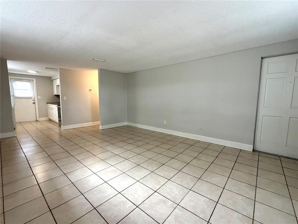 An interior view shows a tiled living area leading to a kitchen with white cabinets — 10022 E WILDER AVENUE UNIT 12, TAMPA, FL