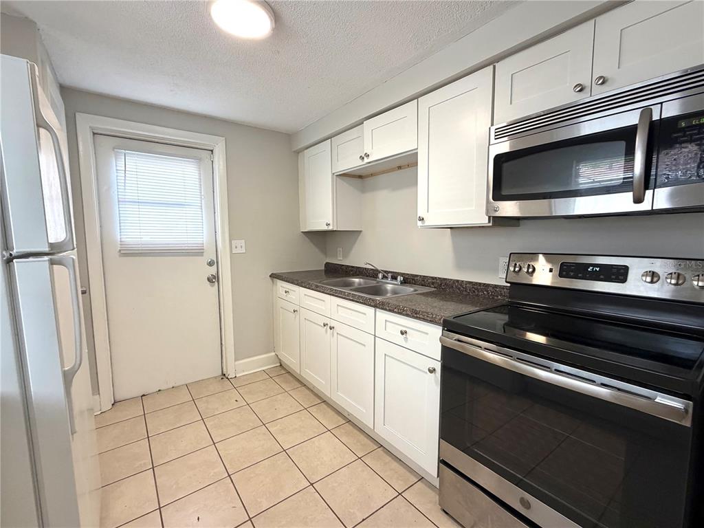 A kitchen with white cabinets, stainless steel appliances, a double sink, and tiled flooring — 10022 E WILDER AVENUE UNIT 12, TAMPA, FL