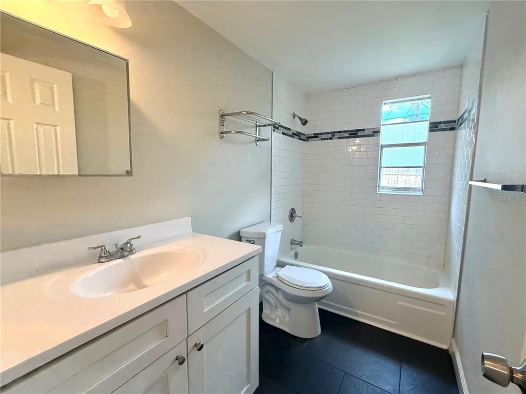 A bathroom features a white vanity, a toilet, and a bathtub with white subway tile — 10022 E WILDER AVENUE UNIT 12, TAMPA, FL