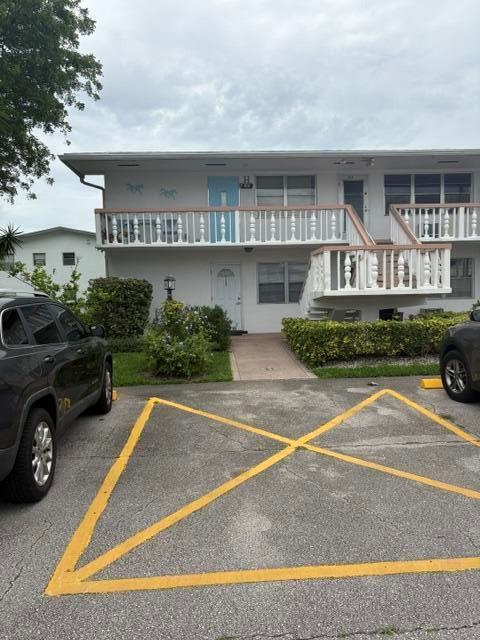 A two-story apartment building features a white exterior, a balcony, and a paved parking area — 145 Northampton # H, West Palm Beach FL 33417, WEST PALM BEACH, FL