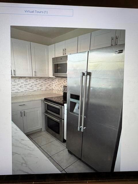 A kitchen features white cabinets, stainless steel appliances, and a tiled backsplash — 145 Northampton # H, West Palm Beach FL 33417, WEST PALM BEACH, FL