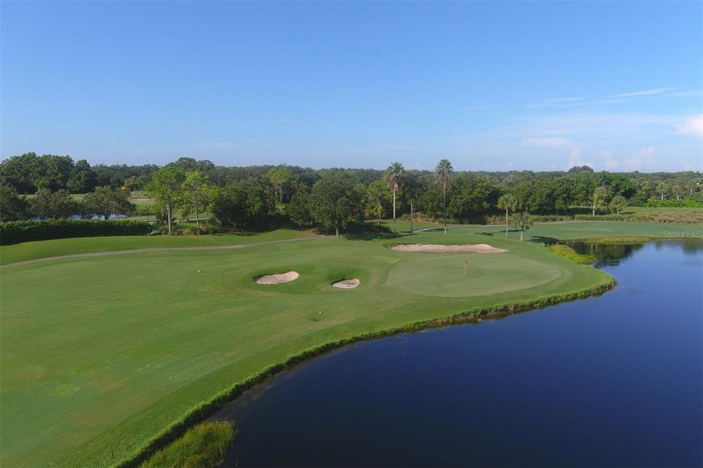 An aerial view of a golf course green surrounded by sand traps and a lake — 7803 GRAND ESTUARY TRAIL UNIT 208, BRADENTON, FL