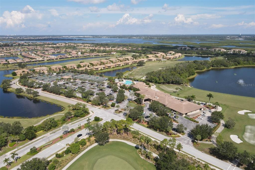 An aerial view of a clubhouse, tennis courts, and golf course surrounded by residential homes — 7803 GRAND ESTUARY TRAIL UNIT 208, BRADENTON, FL
