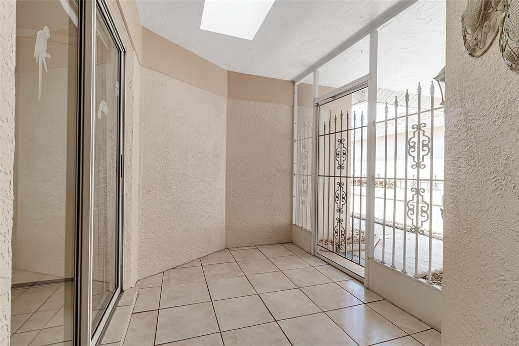 A sunroom with tile flooring, a ceiling fan, and large windows overlooking a lake — 4115 PUTTER PLACE UNIT 4115, BRADENTON, FL
