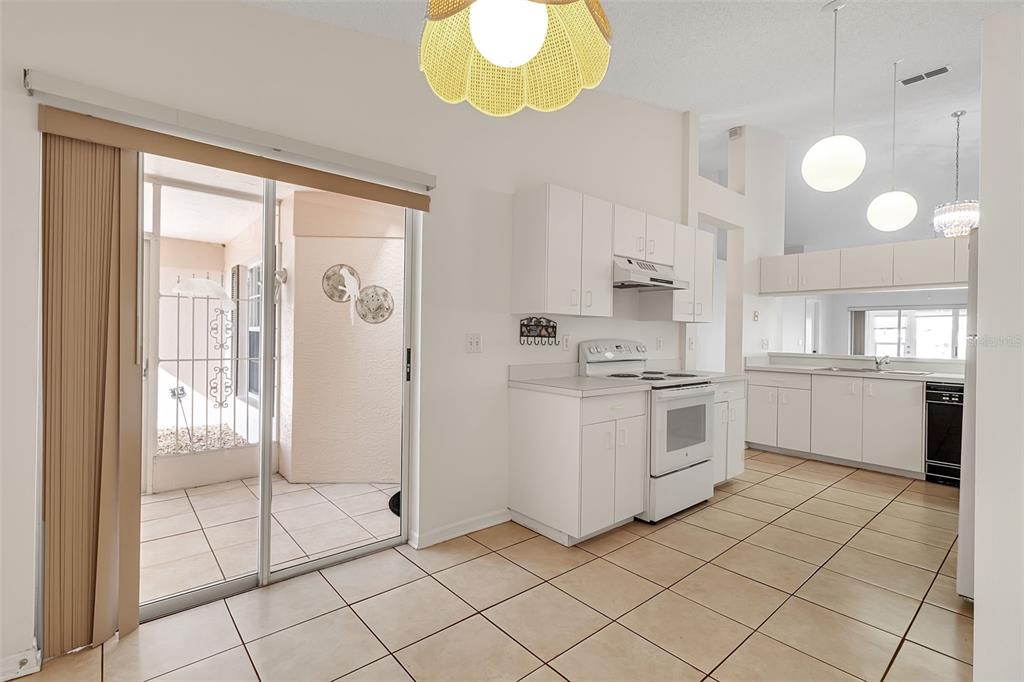 A kitchen with white cabinets, white appliances, tile flooring, and a pass-through window — 4115 PUTTER PLACE UNIT 4115, BRADENTON, FL