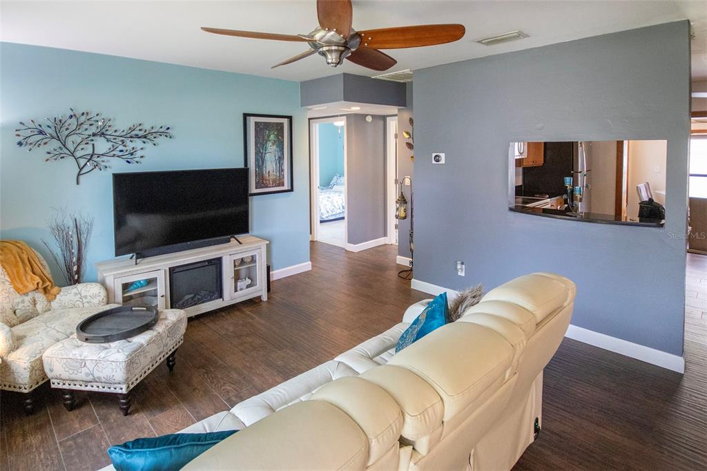 A living room features a white sofa, a television on a console, and blue walls — 1725 BRADSHAW LANE N, ST PETERSBURG, FL