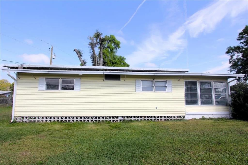 The exterior of a single-story house with yellow siding and a decorative concrete block foundation — 6021 RIDGEWOOD DRIVE, ZEPHYRHILLS, FL