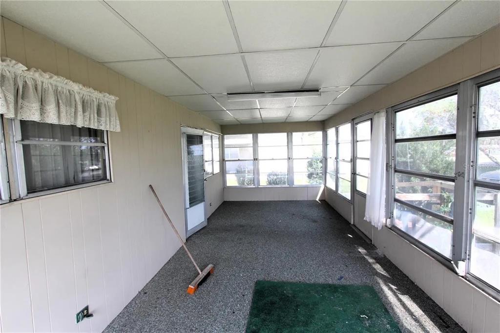 A sunroom with gray carpet, paneled walls, a drop ceiling, and multiple windows — 6021 RIDGEWOOD DRIVE, ZEPHYRHILLS, FL